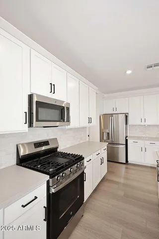 a kitchen with granite countertop white cabinets and stainless steel appliances