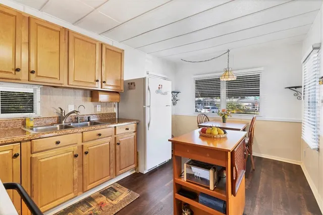 a kitchen with stainless steel appliances granite countertop a refrigerator a sink dishwasher a stove and white countertops with wooden floor