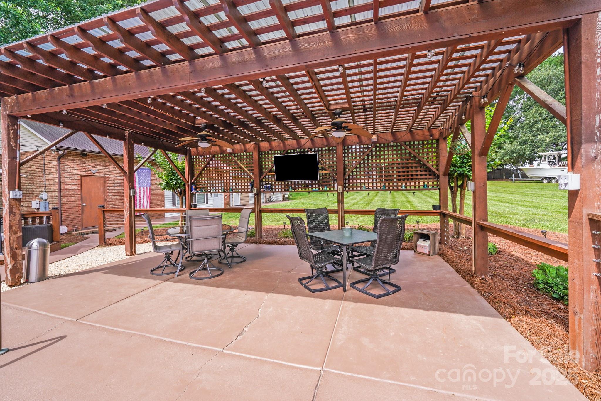 211 Drive Inn Road Locust, NC 28097 - Photo 18 of 48 a view of a patio with table and chairs under an umbrella with a barbeque