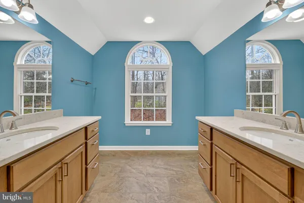 a spacious en suite bathroom with a granite countertop sink a toilet and a mirror