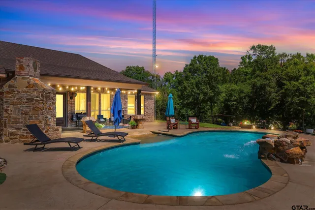 a view of a swimming pool with lawn chairs under an umbrella