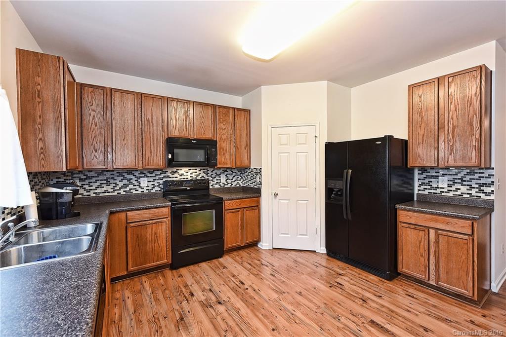 1025 Skillbeck Road Indian Trail, NC 28079 - Photo 8 of 24 a kitchen with granite countertop wooden cabinets a refrigerator and a sink