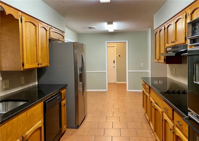 a kitchen with granite countertop a refrigerator and a sink