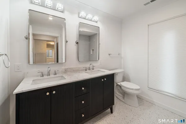 a bathroom with a double vanity sink a toilet and a mirror