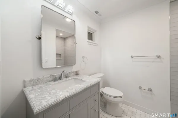 a bathroom with a granite countertop sink a toilet and a mirror