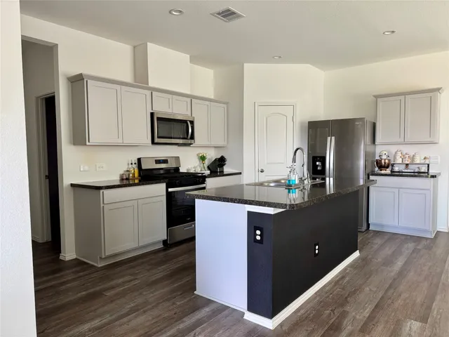 a kitchen with kitchen island granite countertop a refrigerator stove top oven and sink