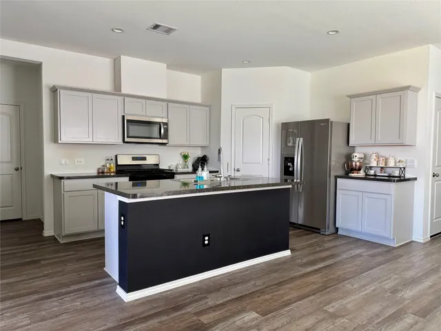 a kitchen with kitchen island white cabinets and stainless steel appliances