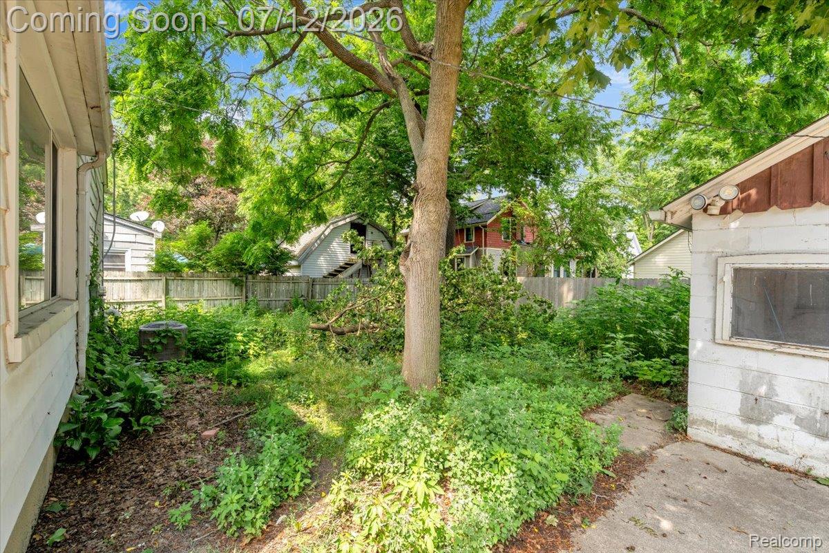 624 North Prospect Road Ypsilanti, MI 48198 - Photo 25 of 28 Mature trees frame a private backyard space featuring a wood fence, concrete pad, and side building with a window