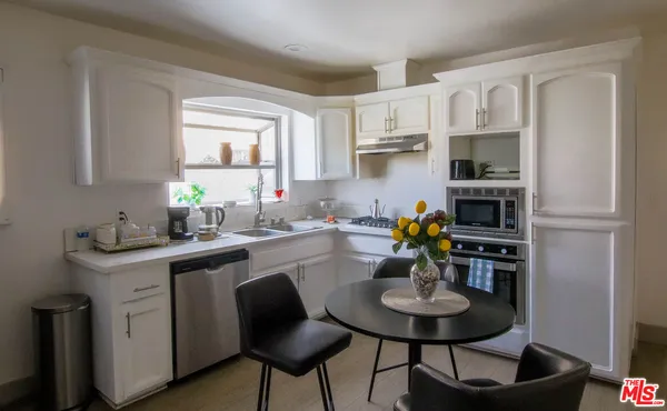 a kitchen with stainless steel appliances a stove a sink dishwasher and white cabinets with wooden floor