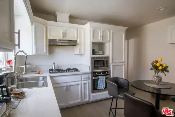 a kitchen with granite countertop a white table chairs and a stove