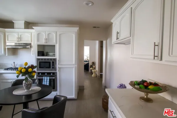 a kitchen with stainless steel appliances a sink a stove a table and chairs