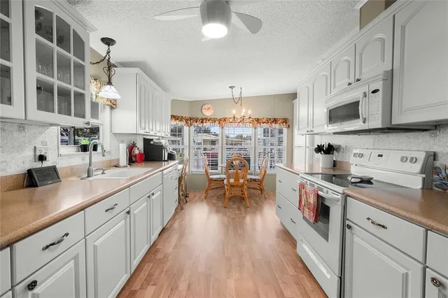 a kitchen with stainless steel appliances a white stove top oven a sink dishwasher and white cabinets with wooden floor