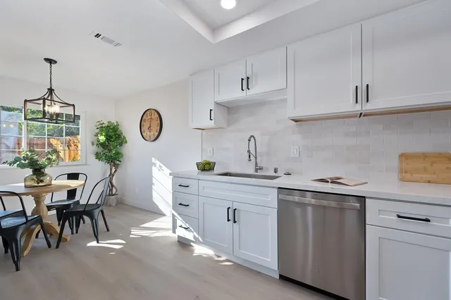 a kitchen with white cabinets and sink