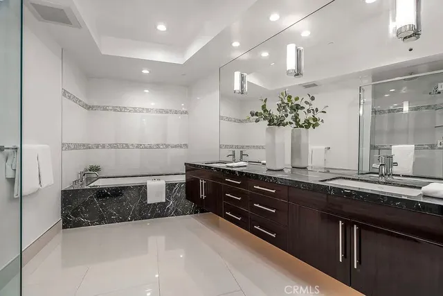 a spacious bathroom with a granite countertop sink a mirror and a bathtub