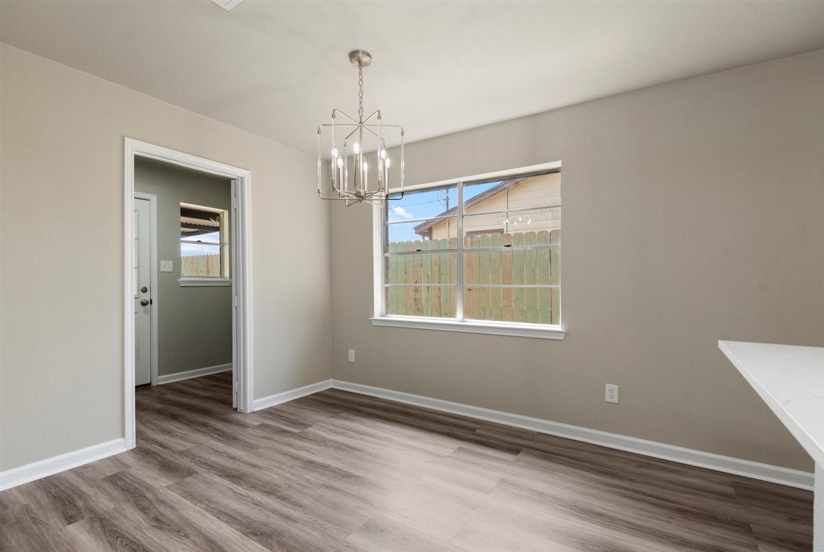 20618 Nannette Lane Spring, TX 77388 - Photo 9 of 32 an empty room with wooden floor chandelier and windows