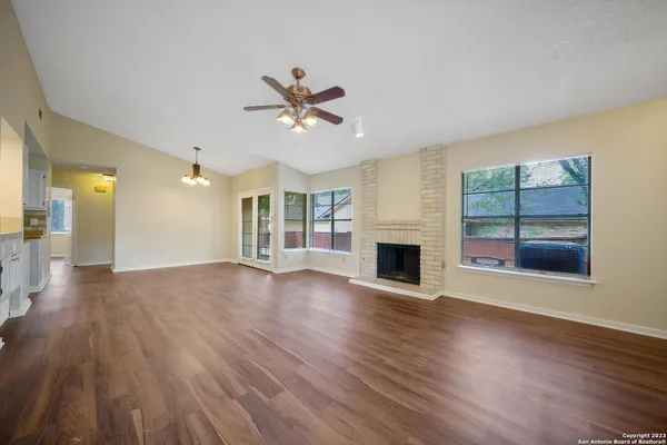 a view of a livingroom with wooden floor a fireplace and windows