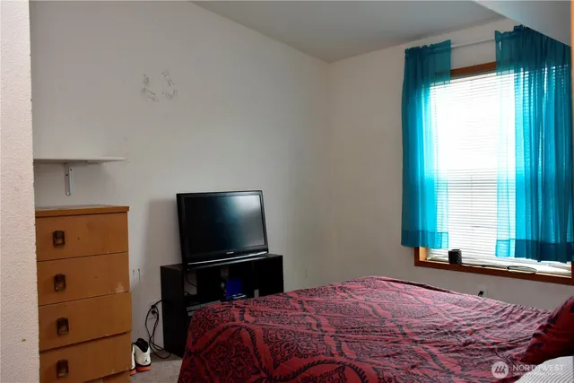 a bedroom with a bed and a flat tv screen on a dresser