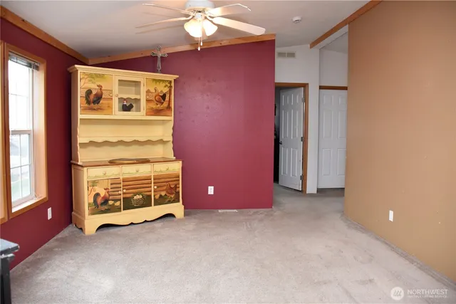 an empty room with windows closet and chandelier fan