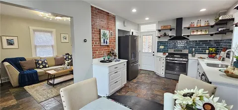 a large living room with stainless steel appliances furniture a rug and a view of kitchen