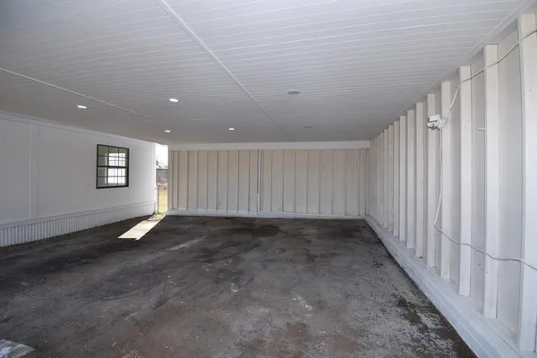 a view of an empty room with wooden floor and window