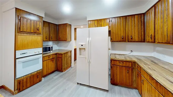 a kitchen with a refrigerator a stove a sink dishwasher and wooden cabinets with wooden floor