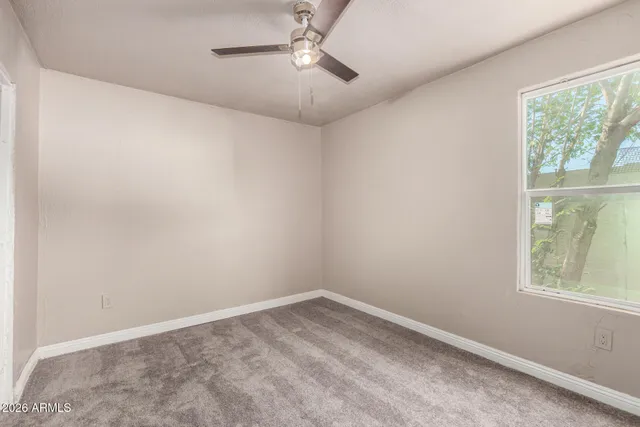 an empty room with a window and ceiling fan