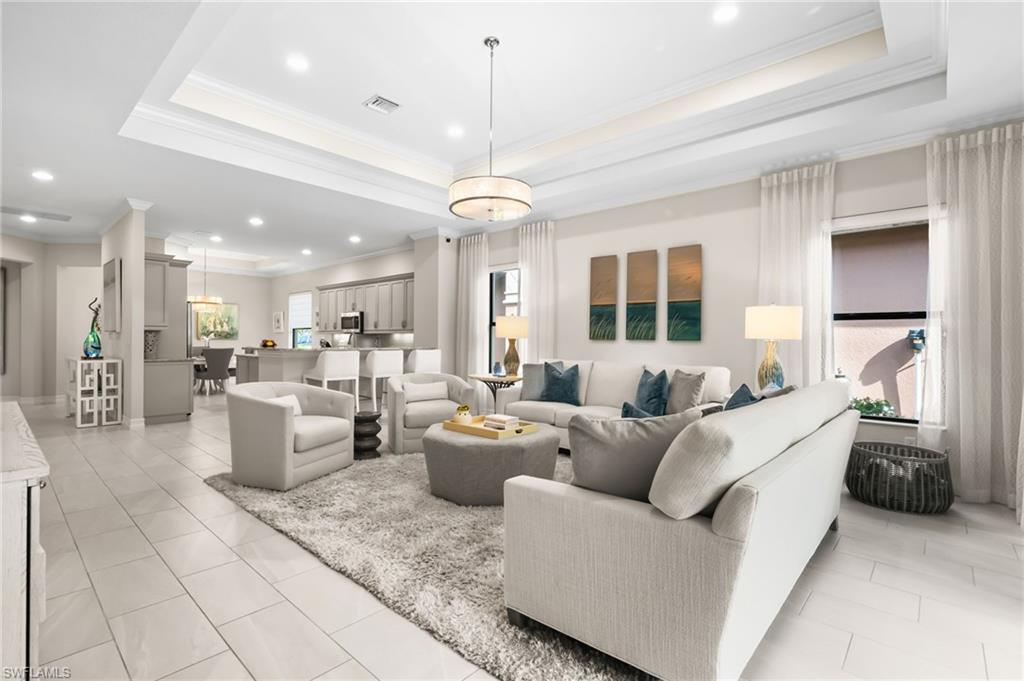 Living room featuring light tile patterned floors, crown molding, and a raised ceiling