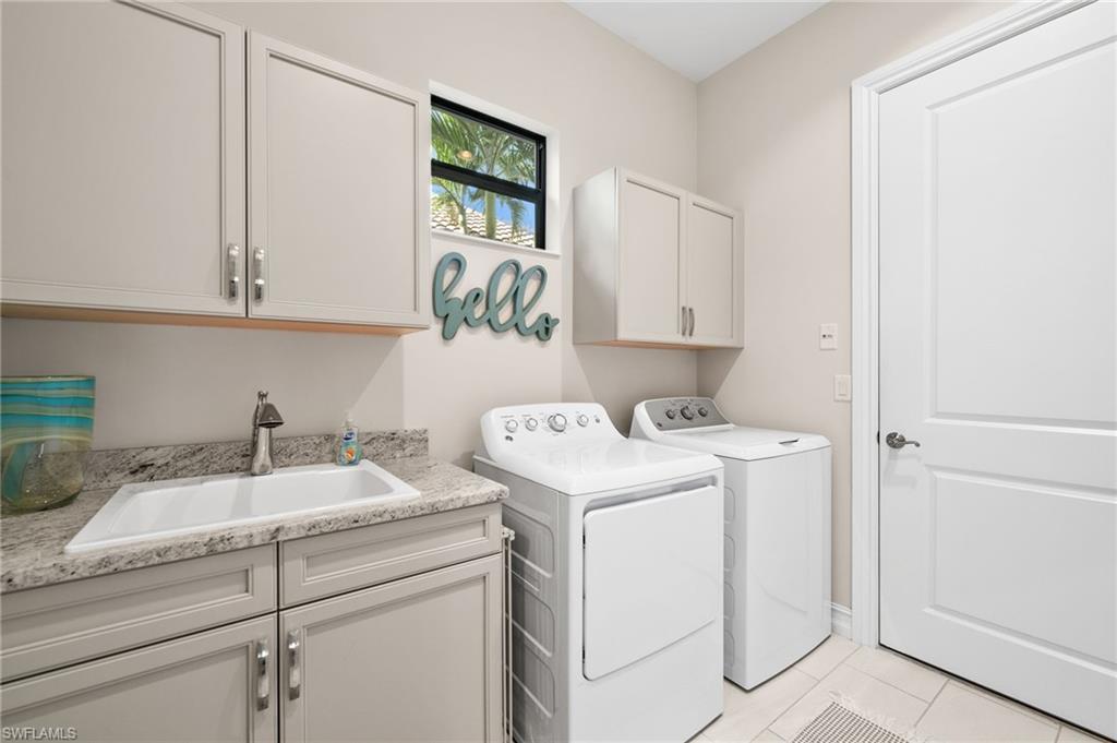 6608 Roma Way Naples, FL 34113 - Photo 25 of 50 Laundry area with sink, light tile patterned flooring, washer and dryer, and cabinets