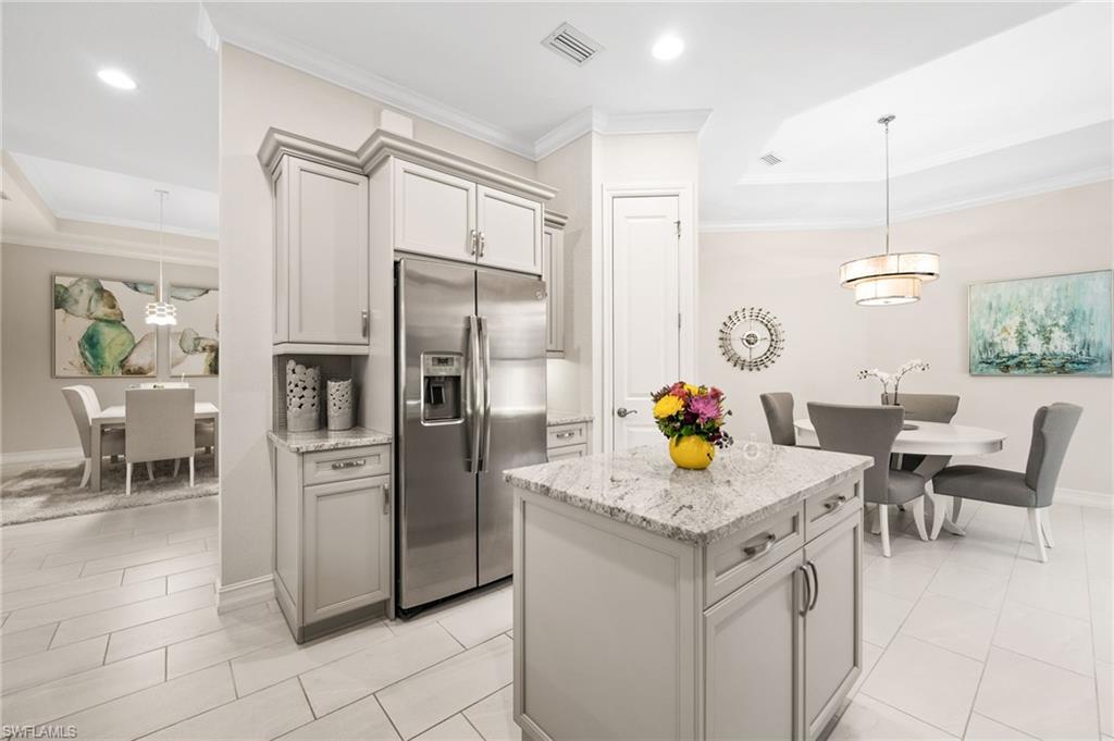 6608 Roma Way Naples, FL 34113 - Photo 3 of 50 Kitchen with stainless steel fridge, gray cabinetry, hanging light fixtures, ornamental molding, and light stone counters
