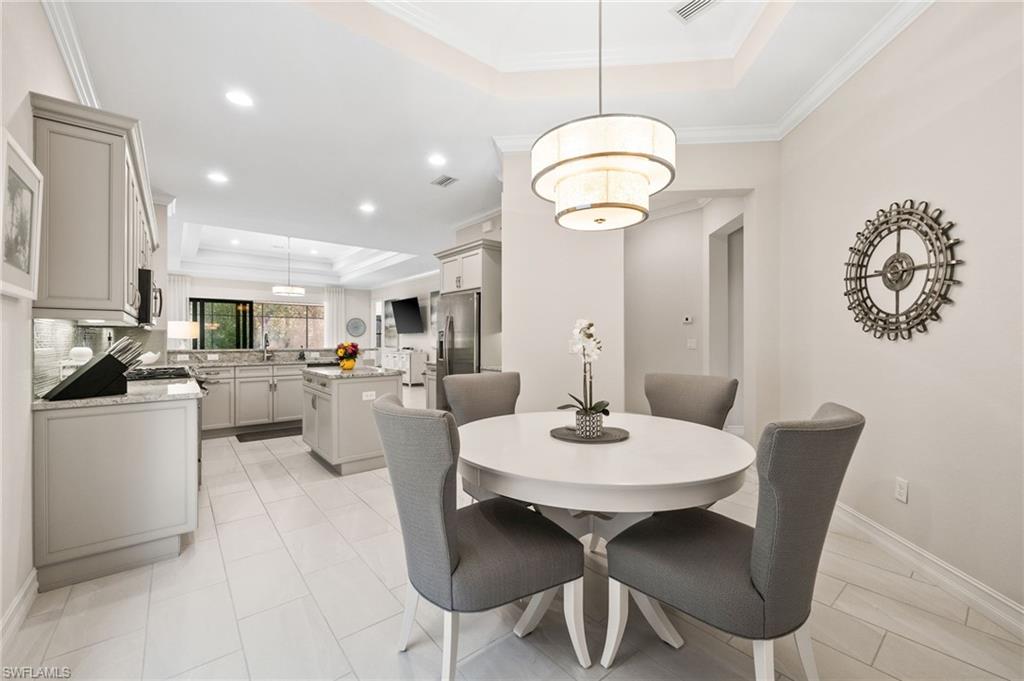 6608 Roma Way Naples, FL 34113 - Photo 6 of 50 Dining space with sink, ornamental molding, and a raised ceiling