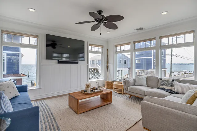 a living room with furniture floor to ceiling window hardwood floor and a flat screen tv