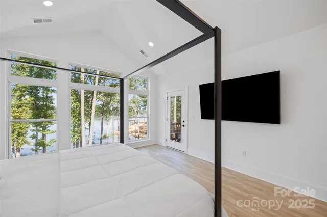 a spacious bedroom with a large window and a flat tv screen