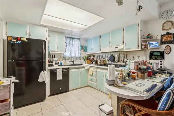 a kitchen with a refrigerator a stove a sink dishwasher and a dining table with wooden floor