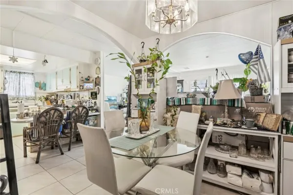 a view of a dining room with furniture a chandelier and kitchen view