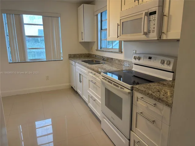 a kitchen with granite countertop white cabinets and white appliances