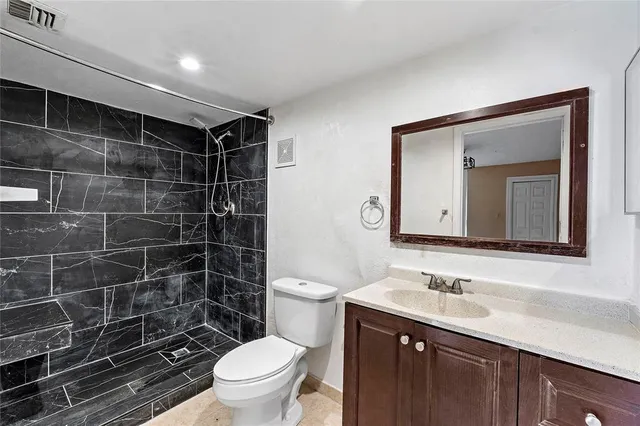 a bathroom with a toilet sink vanity and mirror