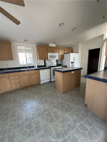 a large kitchen with granite countertop a stove a sink dishwasher and a microwave oven on the counter