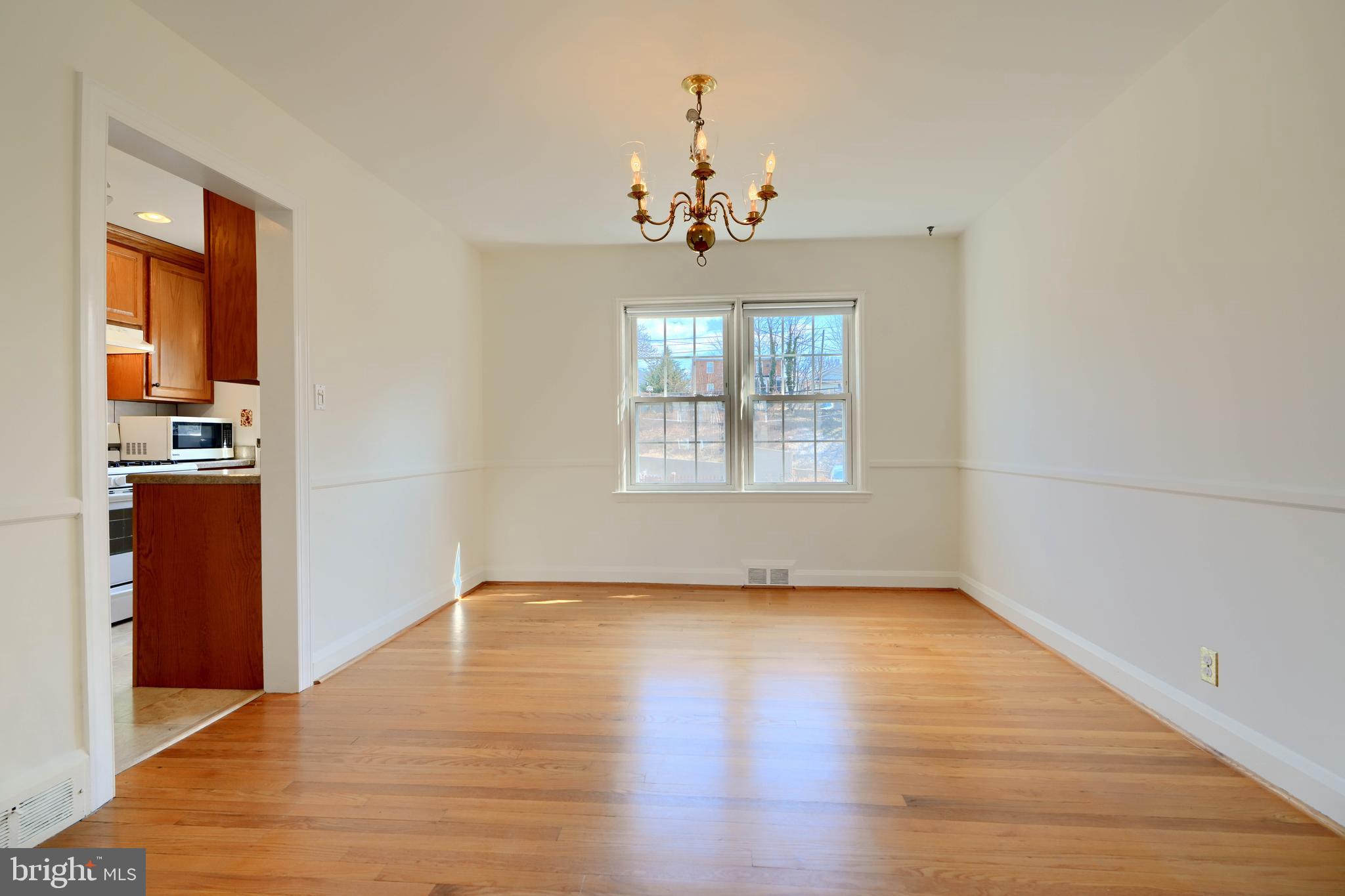 1852 Edgewood Road Towson, MD 21286 - Photo 7 of 31 an empty room with wooden floor chandelier and windows