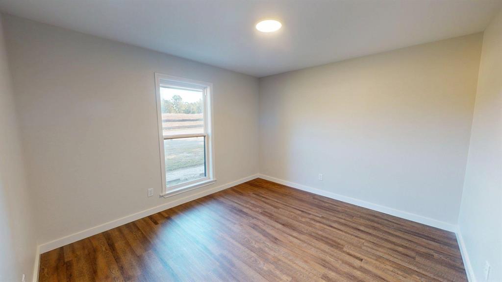 1110 Mill Run Road Athens, TX 75751 - Photo 13 of 32 an empty room with wooden floor and windows