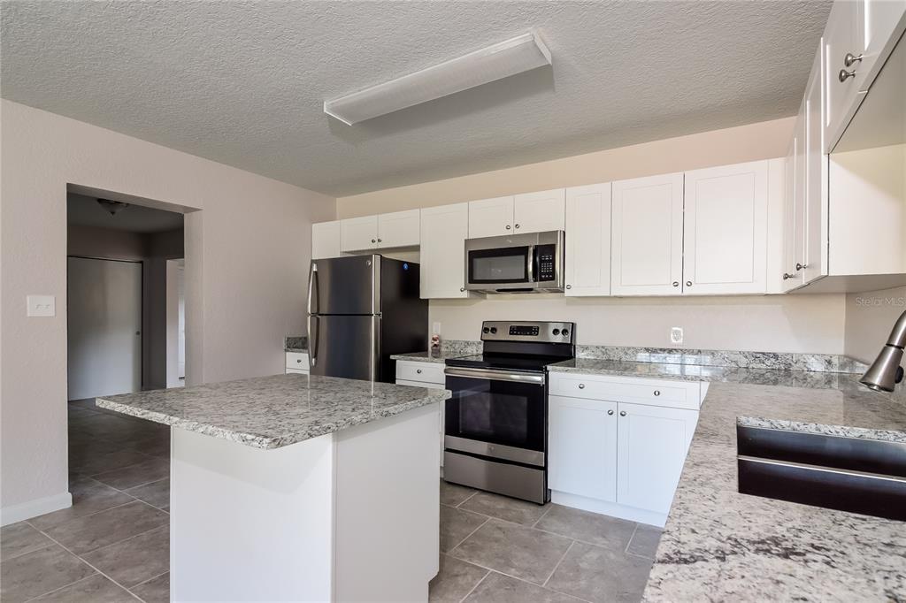 3610 West Leila Avenue Tampa, FL 33611 - Photo 5 of 15 a kitchen with stainless steel appliances granite countertop a stove top oven a sink dishwasher a refrigerator and a microwave
