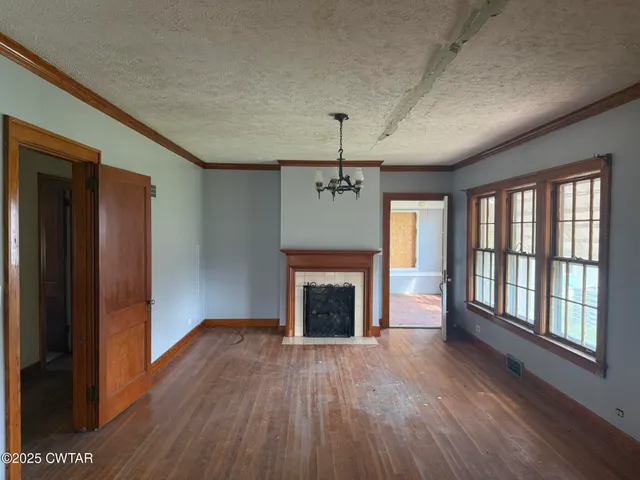 wooden floor fireplace and windows in an empty room