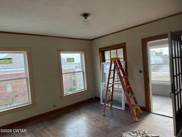 a view of an empty room with wooden floor and windows