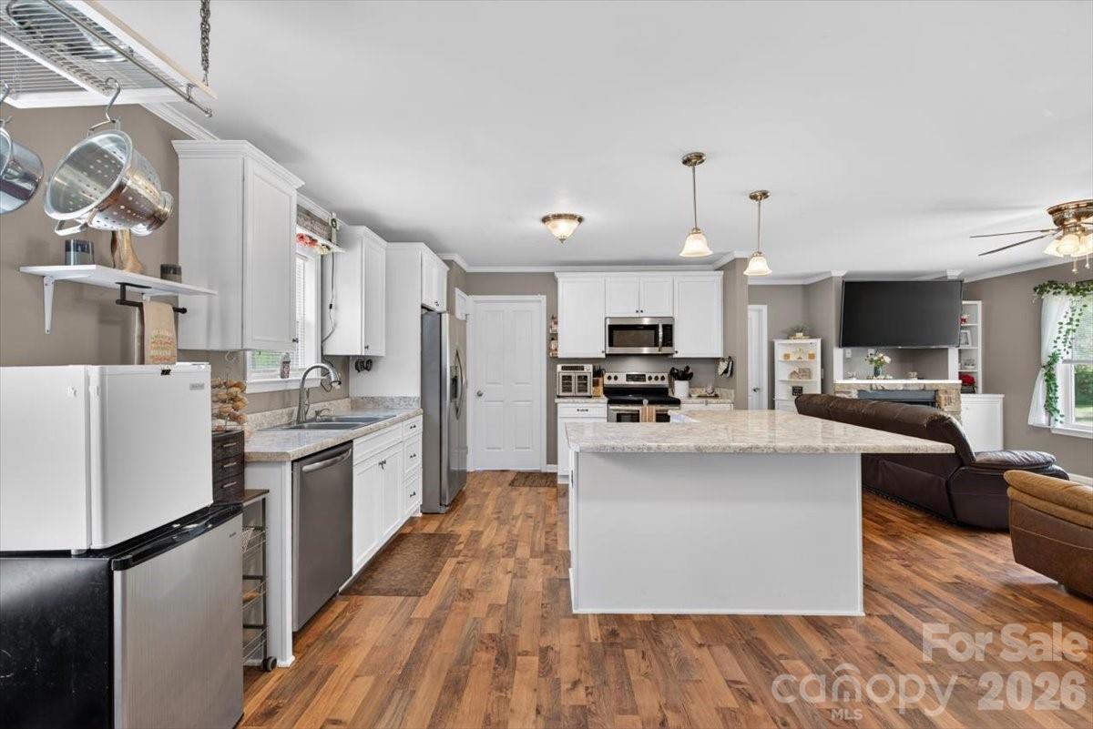 567 Godbey Road Mocksville, NC 27028 - Photo 7 of 38 a kitchen with stainless steel appliances kitchen island granite countertop a refrigerator a stove top oven a sink dishwasher and white cabinets with wooden floor