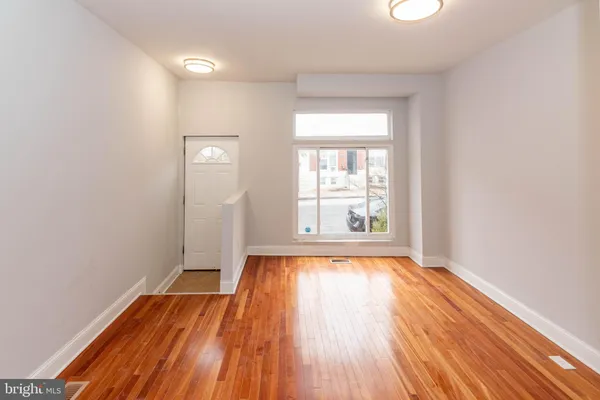 a view of an empty room with wooden floor and a window