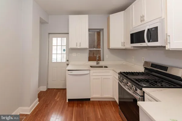 a kitchen with granite countertop a sink cabinets and stainless steel appliances