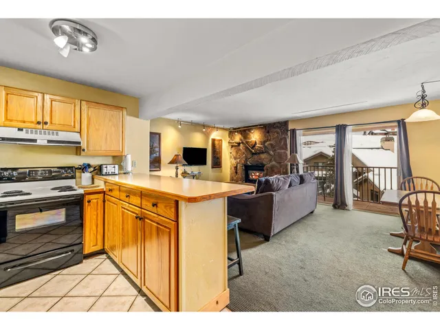 a kitchen with stainless steel appliances granite countertop a stove top oven a sink dishwasher a dining table and chairs with wooden floor