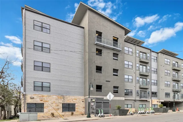 a front view of a building with streets and trees