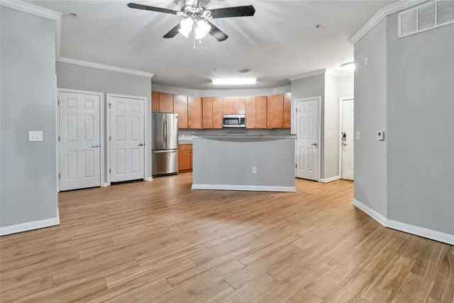 a view of kitchen and empty room with wooden floor
