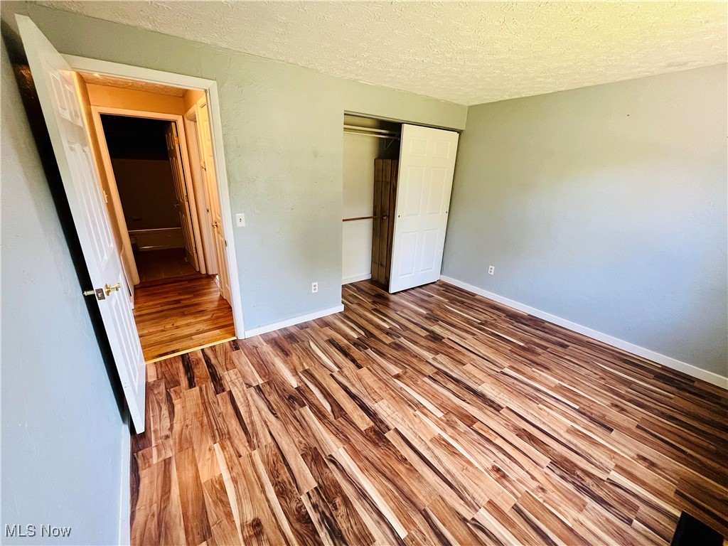 1747 Sterling Road Madison, OH 44057 - Photo 18 of 40 Unfurnished bedroom featuring a closet, wood-type flooring, and a textured ceiling