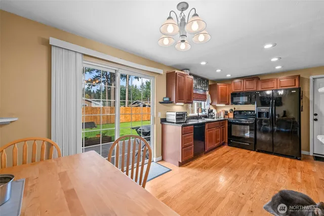 a kitchen with stainless steel appliances kitchen island granite countertop a refrigerator a stove a sink dishwasher a dining table and chairs with wooden floor